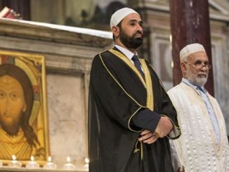 Imame in einer katholischen Kirche vor einer Darstellung von Jesus Christus, der vom Islam