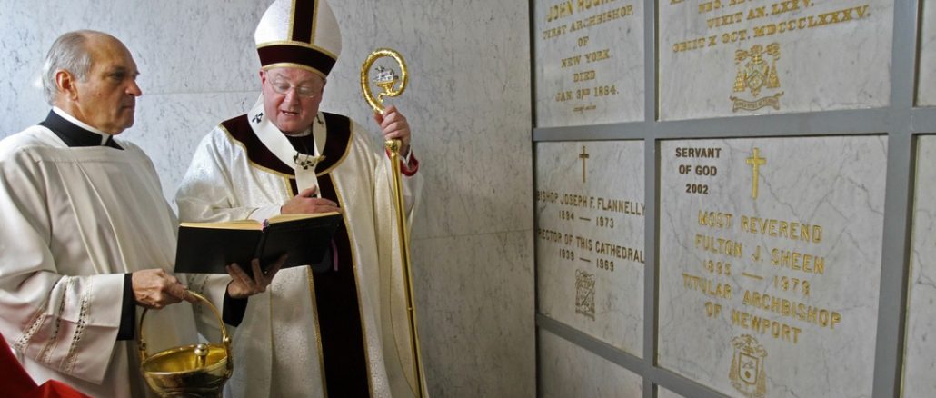 Kardinal Dolan, der Erzbischof von New York, am Grab von Fulton Sheen.