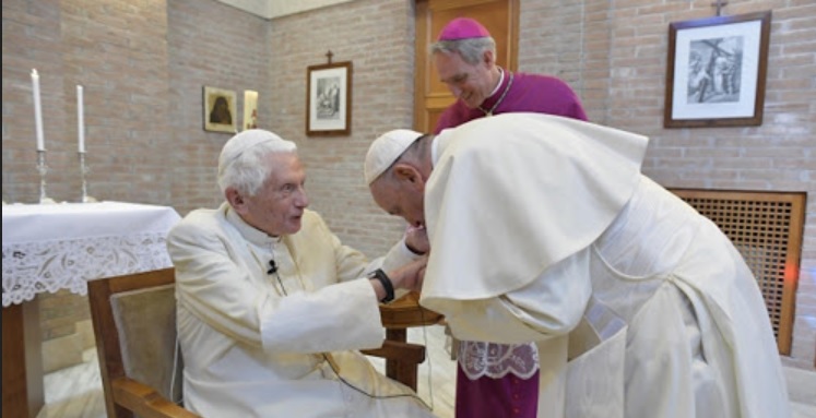 Zwischen sie paßt "kein Blatt"? Papst Franziskus küßt Benedikt XVI. vor dem Photographen die Hand.