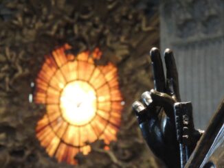 Die segnende Hand der Bronzestatue des heiligen Petrus im Petersdom. Im Hintergrund das Glasfenster mit der Darstellung des Heiligen Geistes der Cathedra Petri von Bernini.