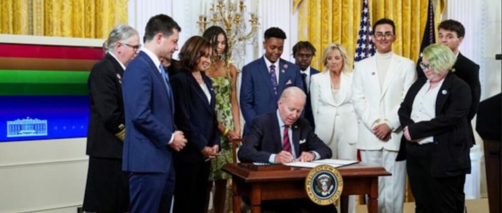 Mit den Homo-Farben im Hintergrund und umringt von "LGBTQI+ and Transgender Peoples" unterzeichnete US-Präsident Biden anläßlich des Homo-Monats neue Anweisungen an die US-Bundesbehörden zur globalen Homo-Förderung.