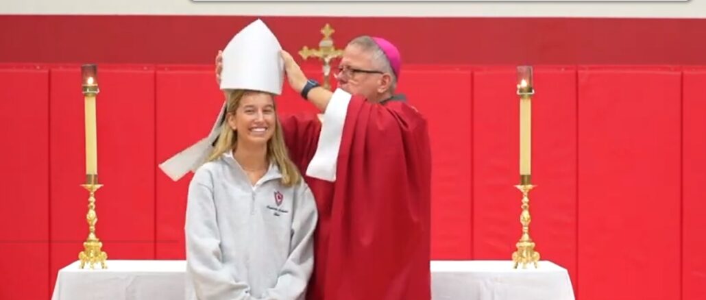 Bischof Michael Martin OFMConv. würgt im Namen der "liturgischen Einheit" den überlieferten Ritus und den knienden Kommunionempfang ab, zeigt selbst aber einen seltsamen Umgang mit seinen liturgischen Insignien. Am 29. August 2024 setzte er scherzhaft während der Predigt einer Studentin seine Mitra auf.