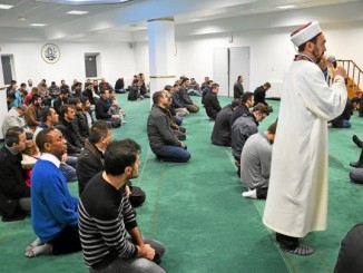 Katholiken und Moslems beim Freitagsgebet in der Moschee. Pfarrer Bigumira im blauen Pullover hinter dem Imam.